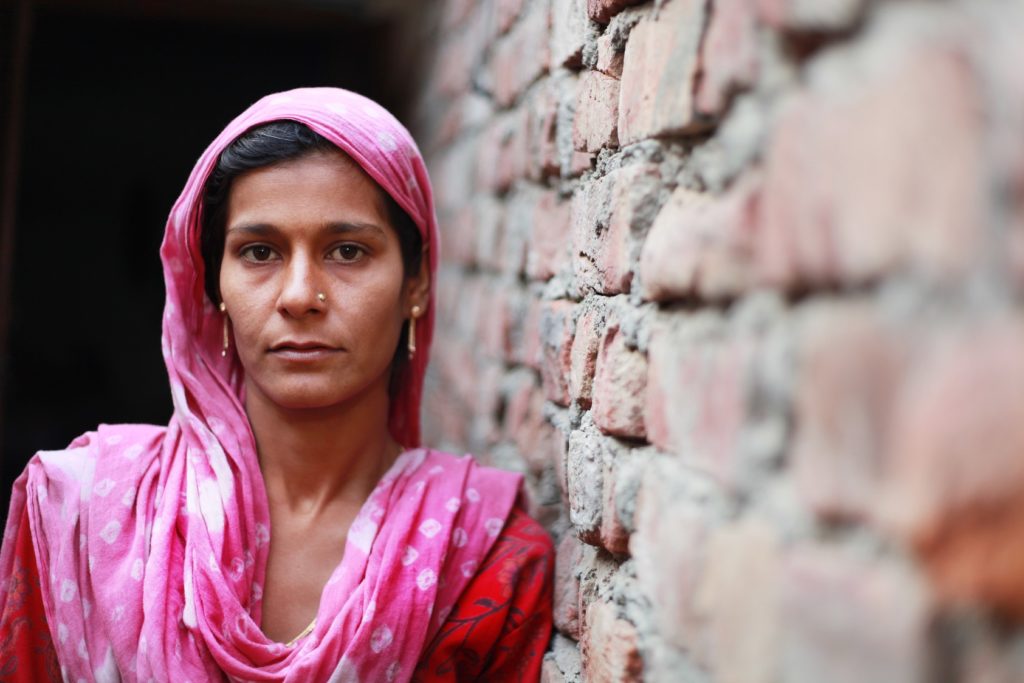 Indian woman leaning against a wall.
