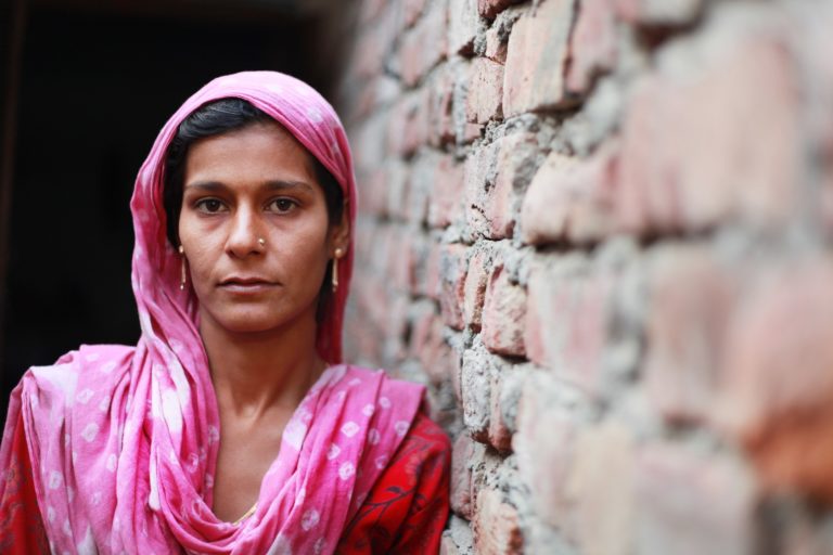 Indian woman leaning against a wall.