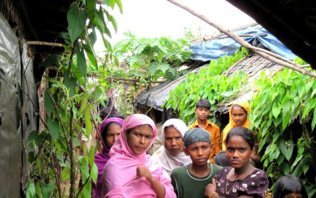refugee women standing in front of a house