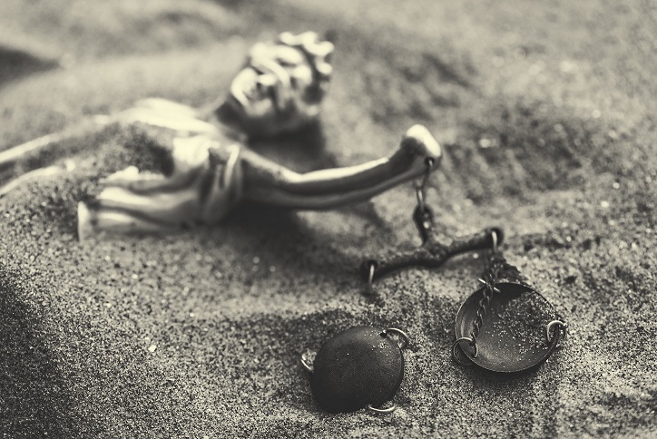 Statue of lady Justice with scale buried in sand