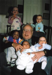 Fr. Paul Marx, founder of PRI, holding the babies of PRI staff members Fr. Paul Marx, founder of PRI, holding the babies of PRI staff members